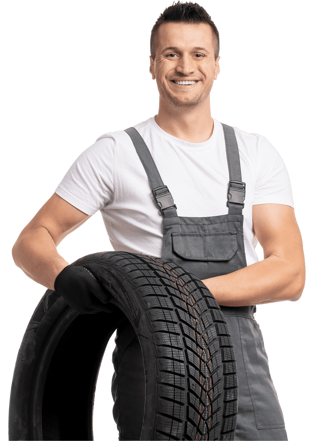 Man in gray overalls holding a tire, smiling at the camera.